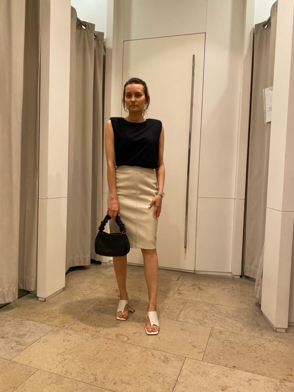 Client in a black top and beige pencil skirt during a fitting